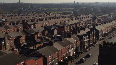 Aerial-view-over-rows-of-historic-terraced-houses-in-Dentons-Green,-St-Helens-with-a-long-road-leading-towards-the-bustling-town-centre