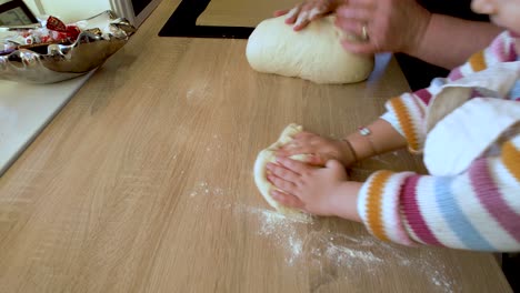 А-little-girl-is-kneading-dough-with-her-grandmother