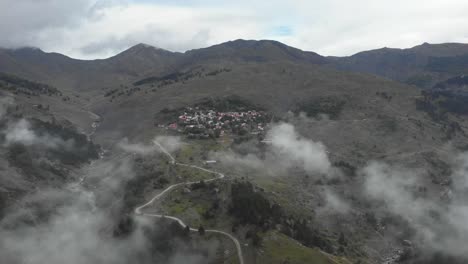 Estableciendo-Un-Video-De-Drones-De-Un-Antiguo-Pueblo-En-Las-Montañas-Entre-Nubes-Y-Picos-De-Montaña,-Un-Cañón-De-Garganta-A-La-Izquierda-Del-Marco-Y-Caminos-De-Montaña