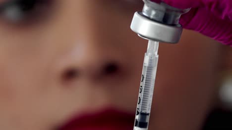 Female-doctor-or-nurse-fills-a-syringe-from-a-vial-of-medication---close-up