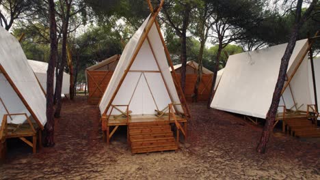 Schiebebilder-Eines-Campingplatzes-Mit-Spitzen-Weißen-Zelten-Auf-Holzplattformen-In-Huelva,-Spanien