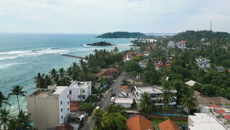 Aerial-shot-of-a-road-in-a-coastal-town-by-the-beach-in-Sri-Lanka,-Mirissa