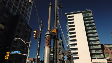Exterior-wide-shot-of-a-tall-machine-drilling-on-site-in-an-urban-setting
