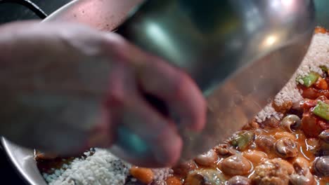 Cook-puts-rice-to-prepare-Spanish-paella
