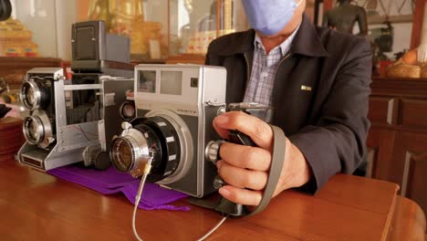 Photographer-wearing-masks-holds-grip-and-trigger-of-Press-Super-23-next-to-Mamiya-C220-Professional