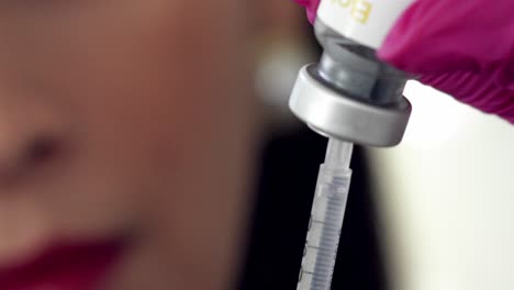 Filling-a-syringe-from-a-vial-of-medication---isolated-close-up