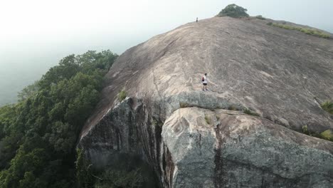 Aerial-extreme-wide-shot-of-man-walking-on-Sigiriya,-Pidurangala-Rock-in-Sri-Lanka