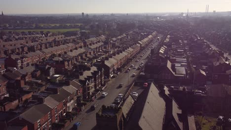 Aerial-view-descends-to-rows-of-historic-terraced-houses-in-Dentons-Green,-St-Helens-with-a-long-road-leading-towards-the-bustling-town-centre