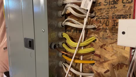 Wires-going-into-electrical-panel-in-unfinished-basement-mounted-on-pressboard