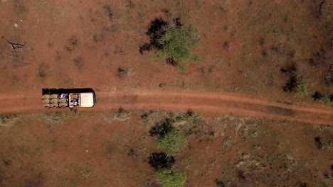 A-drone-ariel-shot-of-a-safari-vehicle-driving-on-a-dusty-arid-dirt-road-in-an-African-safari-park-taking-travellers-on-the-search-for-wild-animals
