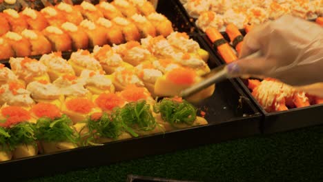 Chef-putting-fresh-sushi-rolls-in-row-on-tray-at-restaurant,-Phitsanulok,-Thailand