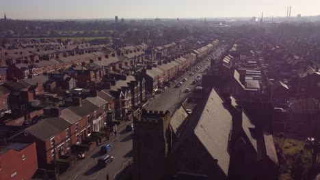 Aerial-view-establishing-rows-of-Victorian-terraced-townhouse-and-church-with-a-long-road-leading-towards-town-centre-at-sunrise