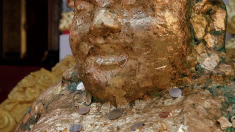 Schwenkansicht-Der-Goldenen-Buddha-Statue,-Die-Mit-Münzen-Bedeckt-Ist,-Die-Als-Glücksbringer-Im-Buddhistischen-Tempel-In-Thailand-Angeboten-Werden