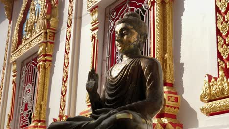 Thai-Protection-Buddha-statue-with-raised-hand-sitting-outside-Buddhist-temple,-Thailand