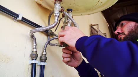 Mittlere-Aufnahme-Eines-Klempners,-Der-Einen-Elektrischen-Warmwasserbereiter-Beobachtet-Und-Repariert