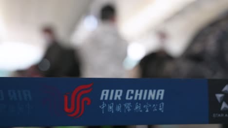 Das-Logo-Der-Chinesischen-Fluggesellschaft-Air-China-Ist-Auf-Einem-Warteschlangenband-Im-Vordergrund-Zu-Sehen,-Während-Sich-Flugpassagiere-An-Einem-Check-in-Schalter-Am-Internationalen-Flughafen-Chek-Lap-Kok-In-Hongkong-Anstellen