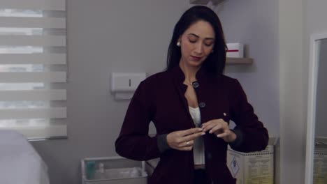 Latina-female-doctor-putting-on-her-smock-or-scrubs-in-her-office