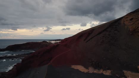 backward-drone-flight-over-the-high-mountains-and-a-black-sand-beach-on-the-volcanic-island-of-lanzarote-on-the-atlantic-ocean