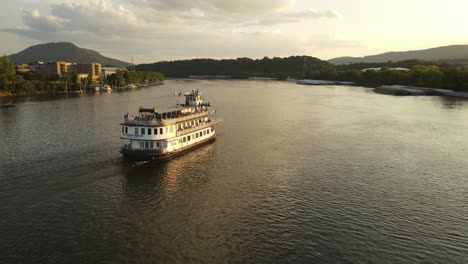 Ferry-boat-sail-in-Tennessee-river-near-Chattanooga-town-during-sunset,-aerial-view