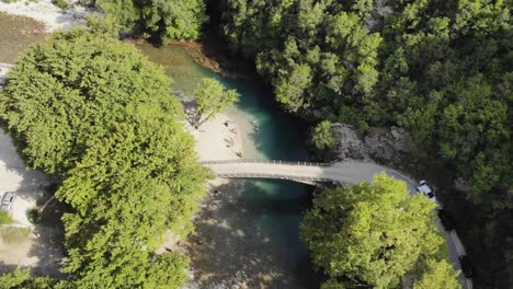 Drohnenvideo-Belauscht-Voidomatis-Fluss,-Papingo,-Griechenland,-Der-über-Eine-Brücke-Fliegt,-Menschen-Am-Ufer