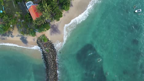 Aerial-top-shot-moving-from-the-sea,-along-a-pier,-to-a-coastal-village