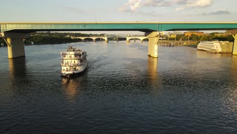 Ferry-boat-in-Tennessee-river-sail-under-bridge,-aerial-drone-view