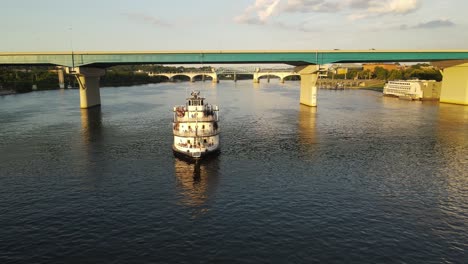 Passenger-ferry-boat-sail-under-bridge-near-American-town,-aerial-drone-view