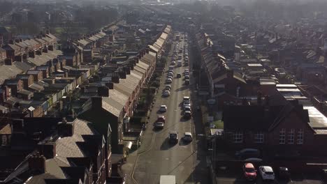Aerial-rising-view-establishing-rows-of-Victorian-terraced-homes-with-a-long-road-leading-towards-town-centre-at-sunrise