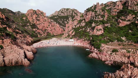 Aerial-otbit-view-of-white-sand-beach-in-a-rocky-bay-on-Sardinia-coast