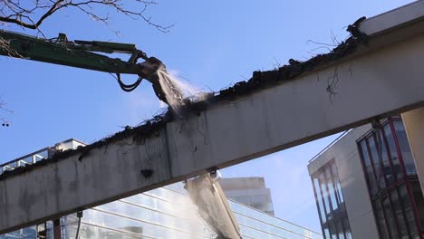 Demolition-crane-spraying-water-on-part-it-is-taking-apart