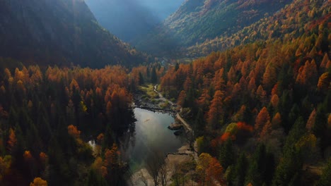 Aerial-View-Of-Calm-Lake-With-Red-Orange-Autumnal-Woodlands-Forest-In-Valley-Of-Val-Di-Mello-In-Lombardy