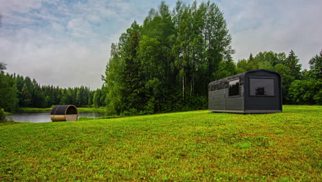 Cozy-wooden-sauna-buildings-on-lake-coast-in-rural-area,-fusion-time-lapse