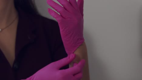 Female-medical-professional-putting-on-pink-latex-gloves