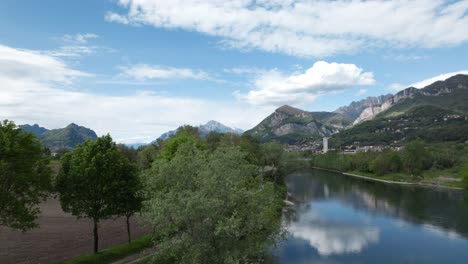 Aerial-View-Of-Scenic-Path-Along-River-In-Calolziocorte-With-Mountain-Views-In-Background