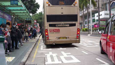 A-bus-pulling-into-busy-bus-stop-downtown-Tsim-Sha-Tsui,-Hong-Kong