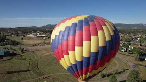 Aerial-View-of-Hot-Air-Balloon-Flying-Above-Green-Landscape,-Pagosa-Springs-Colorado-USA,-Drone-Shot