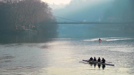Wide-shot-of-Rowers-in-front-of-a-foggy-bridge-in-France,-Lyon-during-the-cold-season