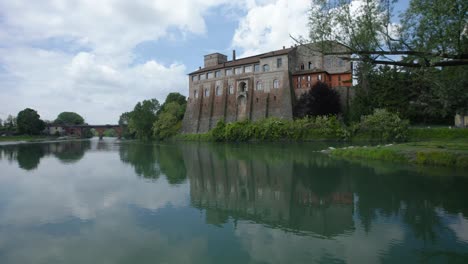 Aerial-shot-over-a-lake-and-an-old-building-in-Cassano-d'adda-in-Lombardy,-Italy
