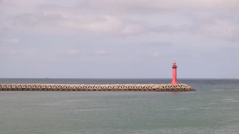 Wide-angle-shot-lighthouse-on-pier-surrounded-by-endless-ocean-water