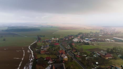 Aerial-bird's-eye-view-of-a-small-rural-village-of-houses-and-farms-in-winter-sunny-day