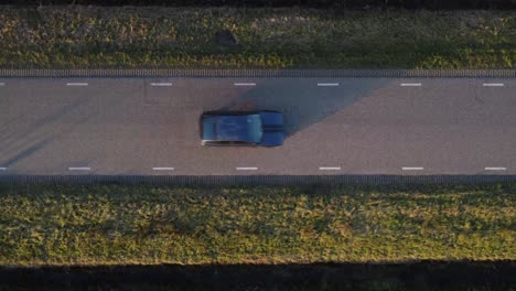 Above-drone-shot-of-car-driving-down-a-road