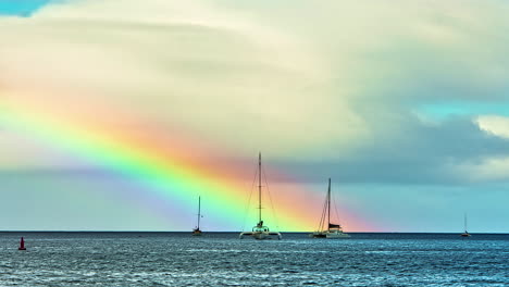 Vibrant-bright-rainbow-rise-above-ocean-water-with-small-boats,-fusion-time-lapse