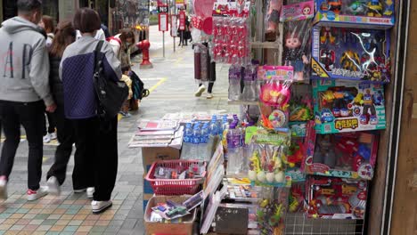 Asian-people-walking-past-toy-street-market-in-Hong-Kong,-China