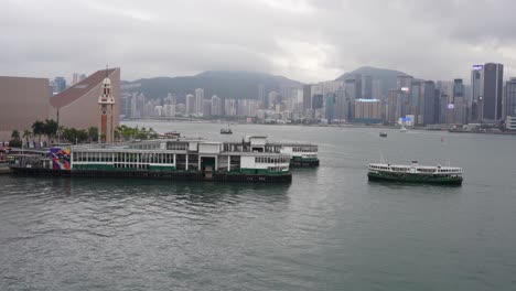 Star-Ferry-arrives-at-pier-on-cloudy-day-in-Hong-Kong,-wide-static