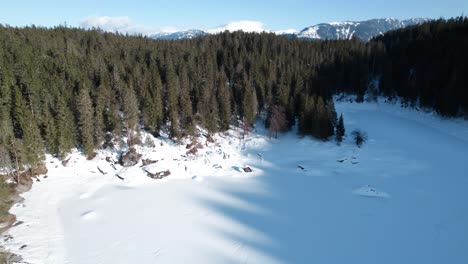 Luftaufnahme-Des-Schneebedeckten,-Gefrorenen-Wintercaumasees-Mit-Waldbäumen-Im-Blick