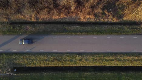 High-above-drone-shot-of-car-driving-by-on-side-road