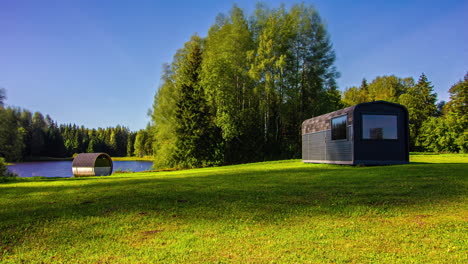 Modern-sauna-buildings-on-lake-side-in-rural-area,-fusion-time-lapse-of-sunny-day