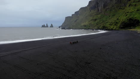 Aerial:-Slow-orbit-shot-with-group-of-tourists-riding-horses-on-the-beach-of-Vik-in-Iceland