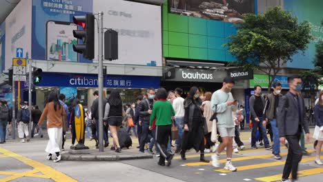Asian-people-crossing-busy-street-wearing-mask-in-Tsim-Sha-Tsui,-Hong-Kong