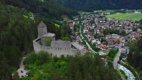 Landscape-of-a-castle-in-a-village,-wooded-valley-between-mountains-and-a-river